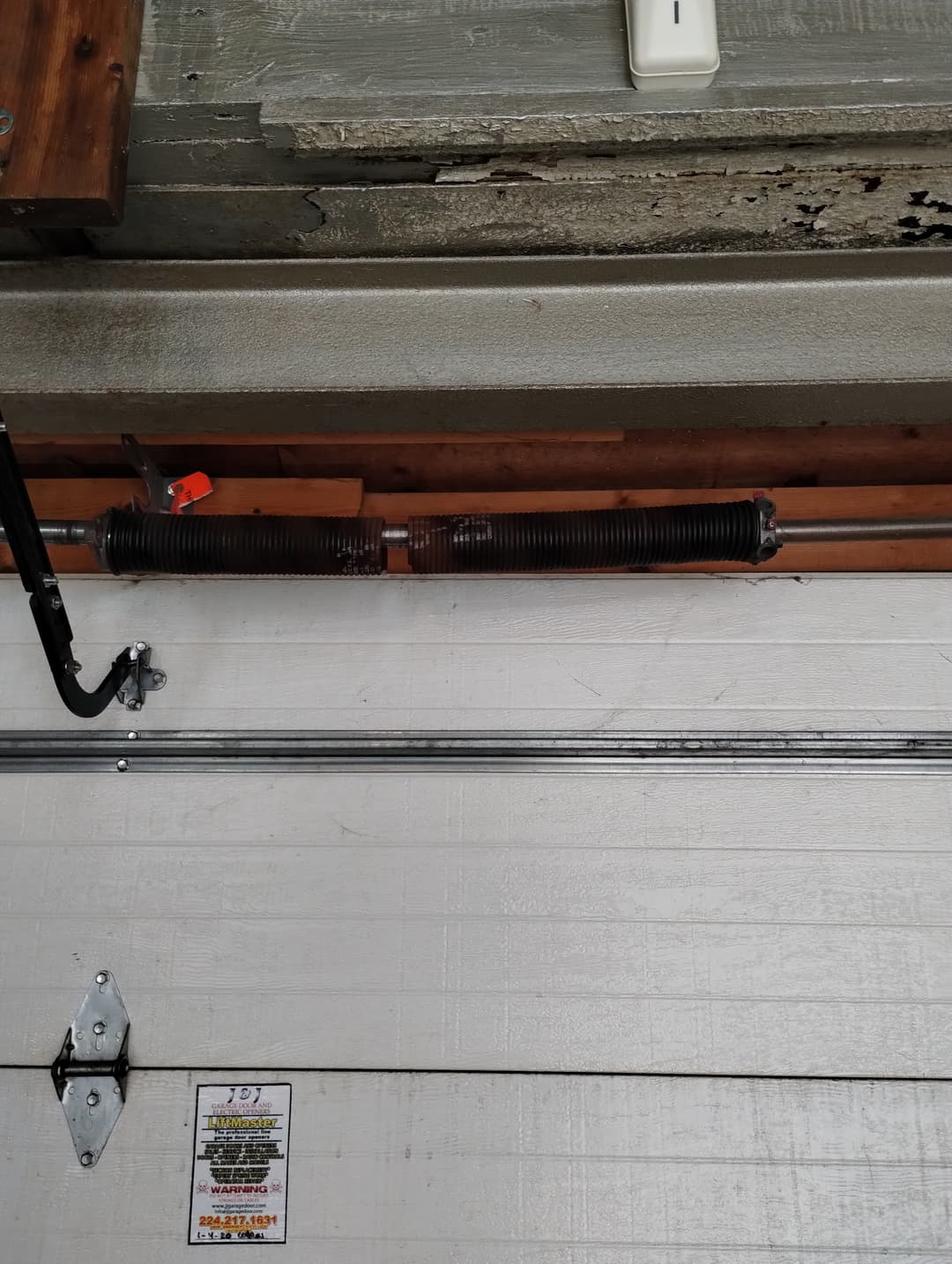 Garage door torsion spring and shaft installed above the door.